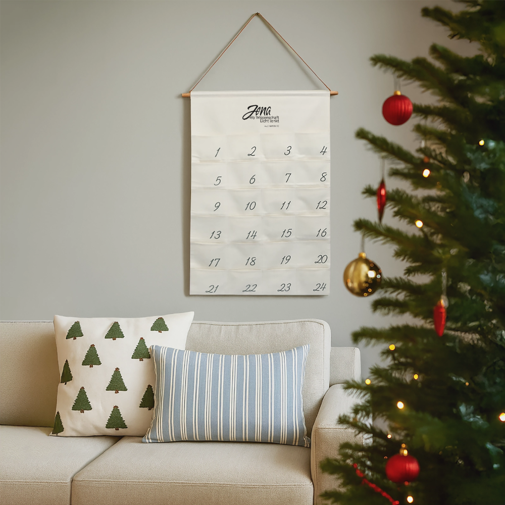 Jena Adventskalender im Jena.Lichtschrift-Design neben einem geschmückten Weihnachtsbaum im Wohnzimmer